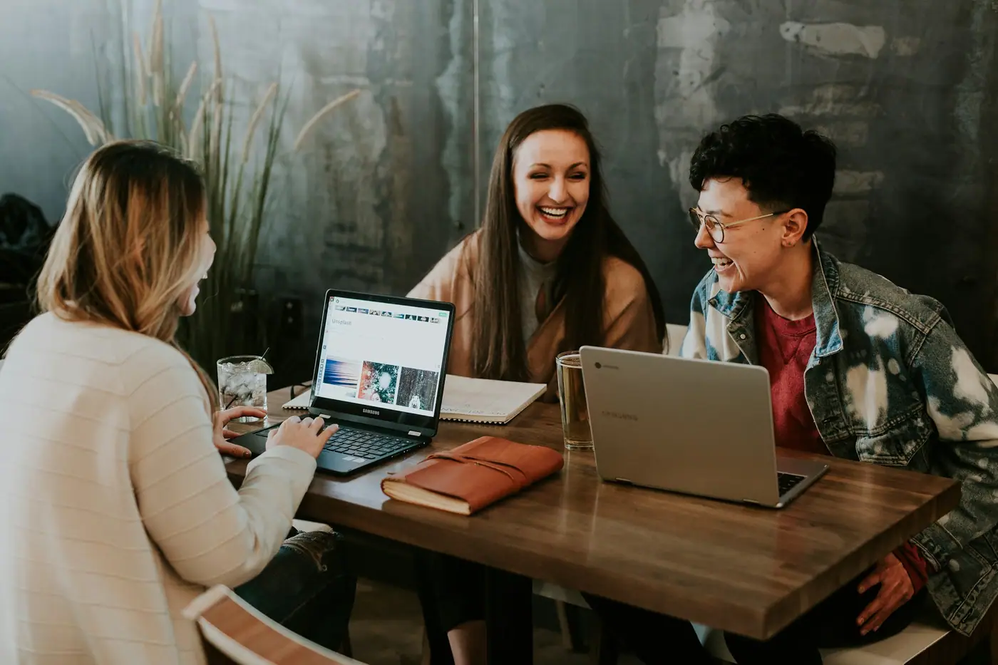 Tres profesionales conversando y sonriendo mientras trabajan con sus laptops