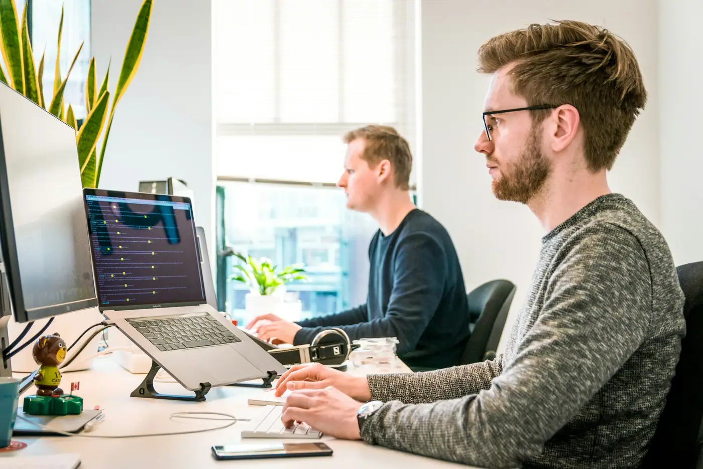 Dos personas trabajando frente a computadoras en una oficina